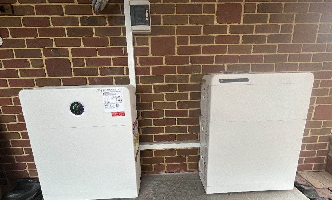 Two home batteries installed side by side on a brick wall