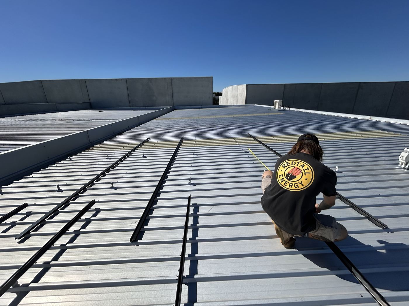 Redtail Energy installer measuring out solar rails on a commercial roof